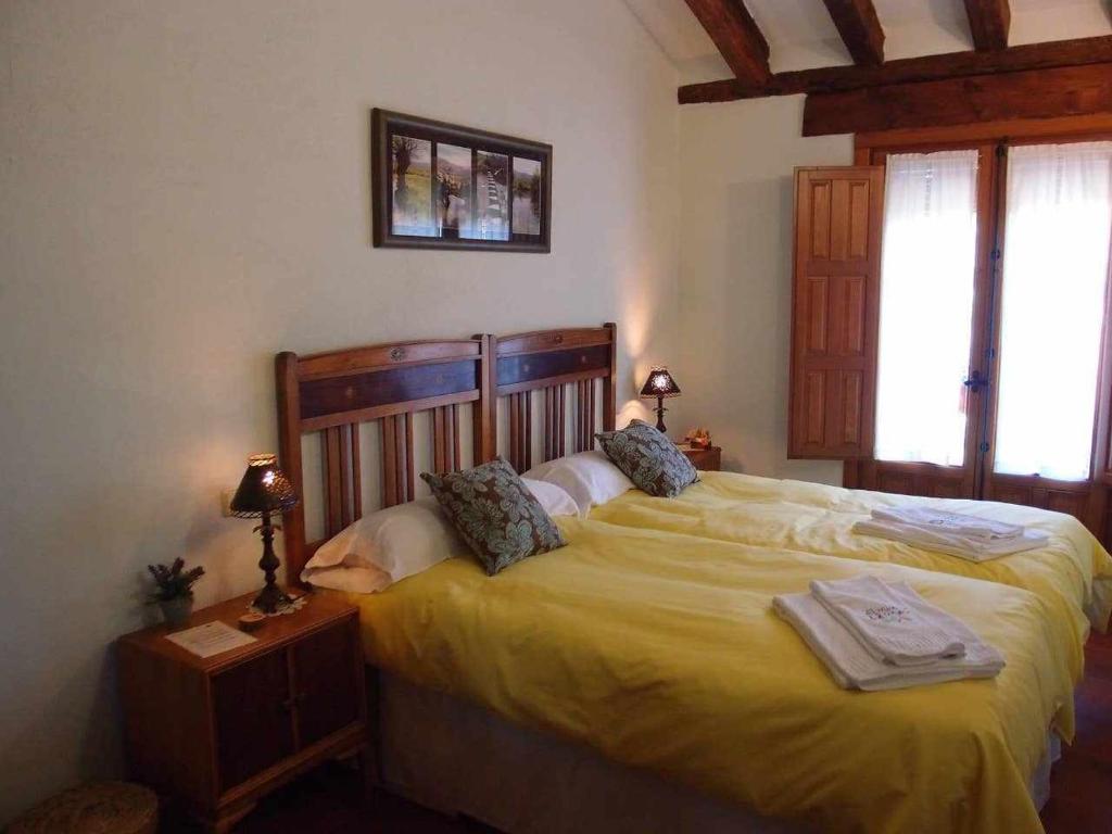 a bedroom with a large bed with a yellow bedspread at Agroturismo El Mirador de la Cigüeña in Cabanillas del Monte