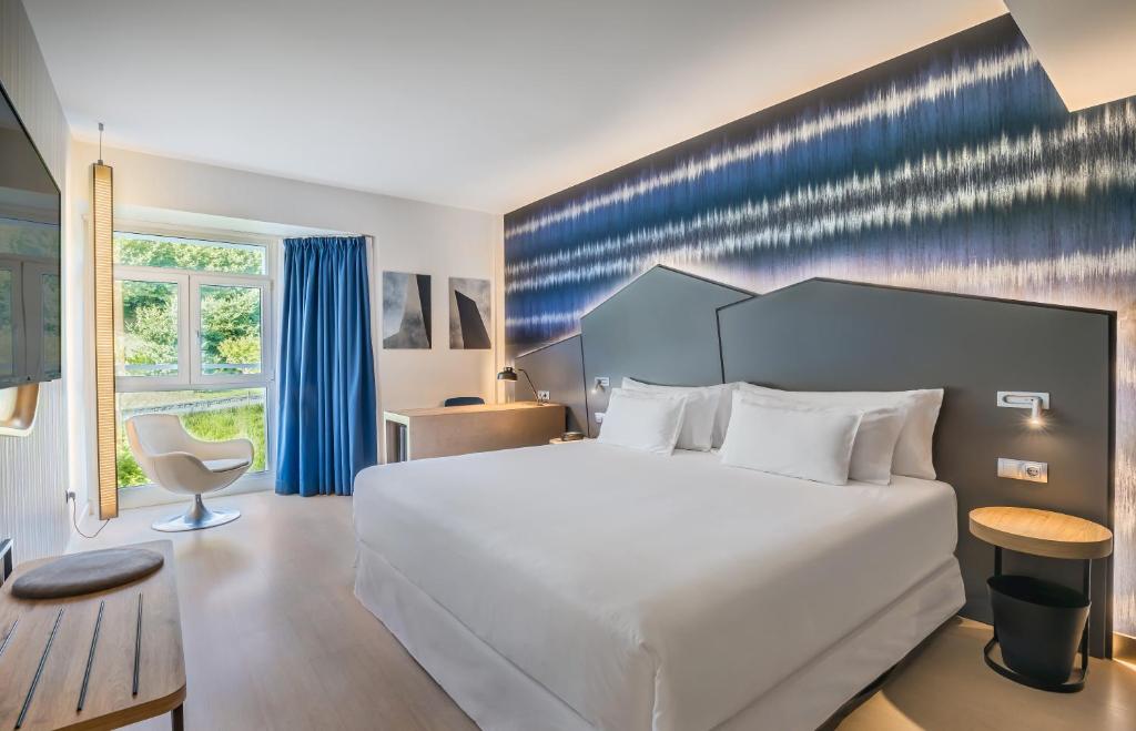 a bedroom with a large white bed and a chair at Barceló Costa Vasca in San Sebastián
