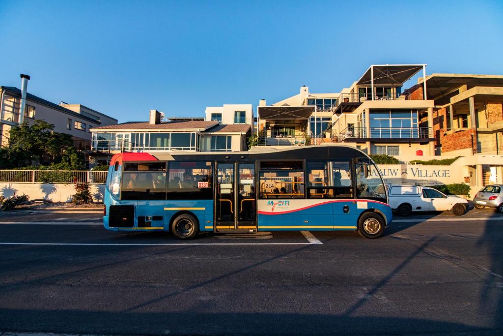 a bus is parked on a city street at Blaauw Village Guest House in Bloubergstrand