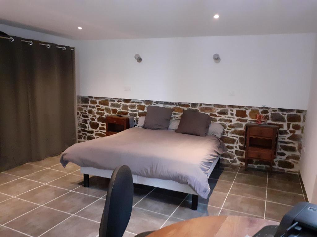 a bedroom with a bed and a stone wall at Le Bonheur En Bretagne in Rouillac