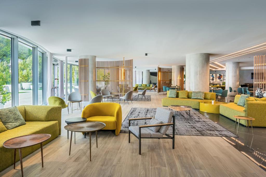 a lobby with yellow and green furniture and tables at Barceló Costa Vasca in San Sebastián