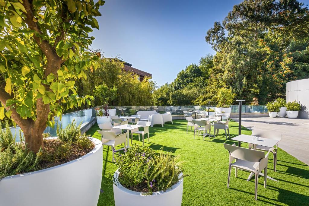 a patio with tables and chairs and a tree at Barceló Costa Vasca in San Sebastián