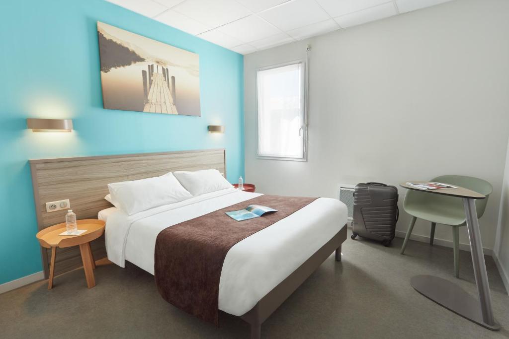 Un dormitorio con una cama grande y una mesa. en Ashley Hotel Le Mans Sud en Ruaudin