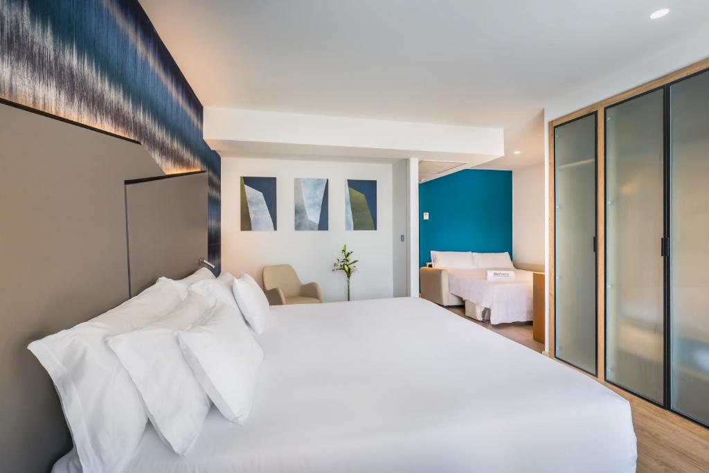 a bedroom with a large bed with white pillows at Barceló Costa Vasca in San Sebastián