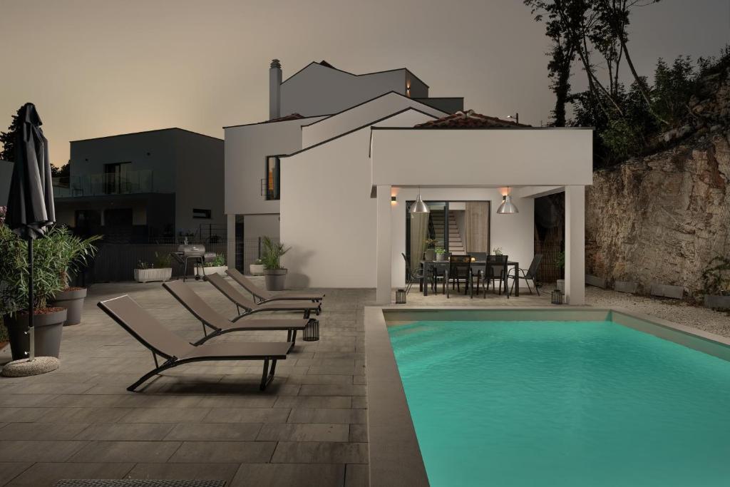 a swimming pool with lounge chairs next to a house at Villa San Polo Max in Divšići