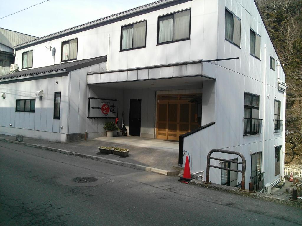ein weißes Gebäude mit einer großen Tür auf einer Straße in der Unterkunft Shima Onsen Ichigekan in Nakanojo