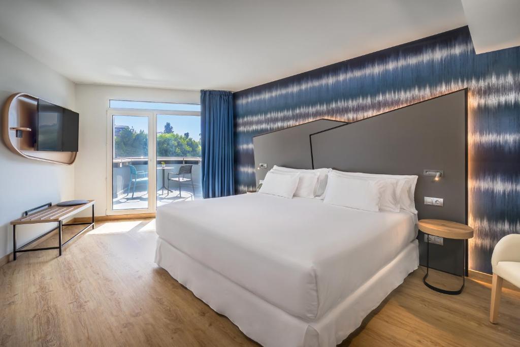 a bedroom with a large white bed and a balcony at Barceló Costa Vasca in San Sebastián