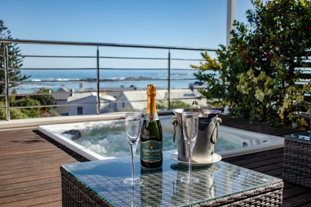 a bottle of champagne and two glasses on a table at Blaauw Village Guest House in Bloubergstrand