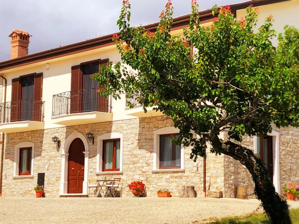 une maison en pierre avec un arbre en face de celle-ci dans l'établissement Agriturismo Casale Cerere, à Lacedonia