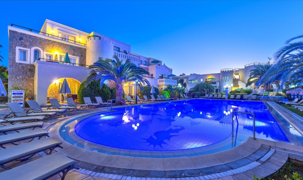 einen Pool in einem Resort mit Stühlen und Palmen in der Unterkunft Hotel Castle Suites in Platanias