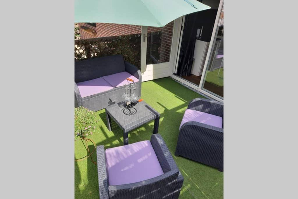 een patio met een bank, een tafel en een parasol bij Brabants Genoegen Heeswijk Dinther in Dinther