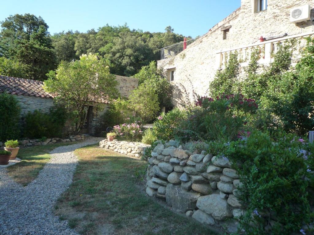 un jardin en face d'un bâtiment avec un mur en pierre dans l'établissement La Petite Grange, à Reynès