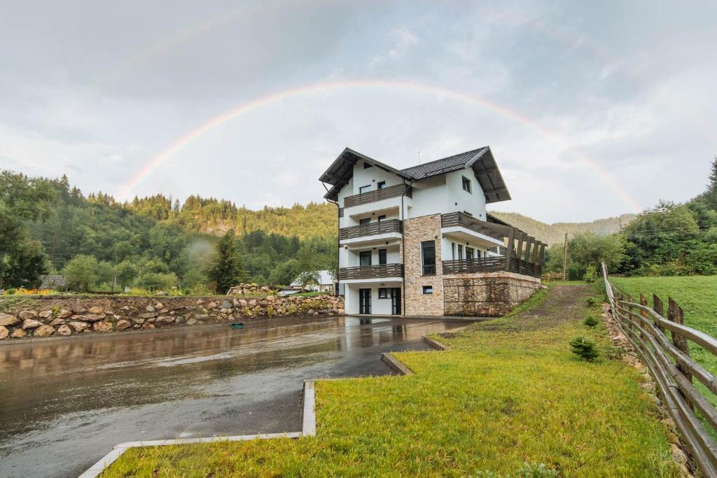 un arc-en-ciel sur une maison avec une rivière dans l'établissement Comoara Rarăului, à Câmpulung Moldovenesc