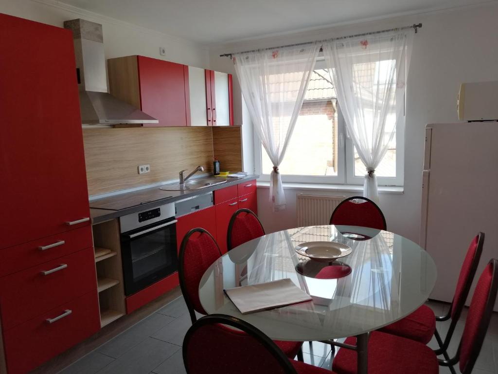 cocina con mesa de cristal y armarios rojos en Apartment AMS en Oststeinbek