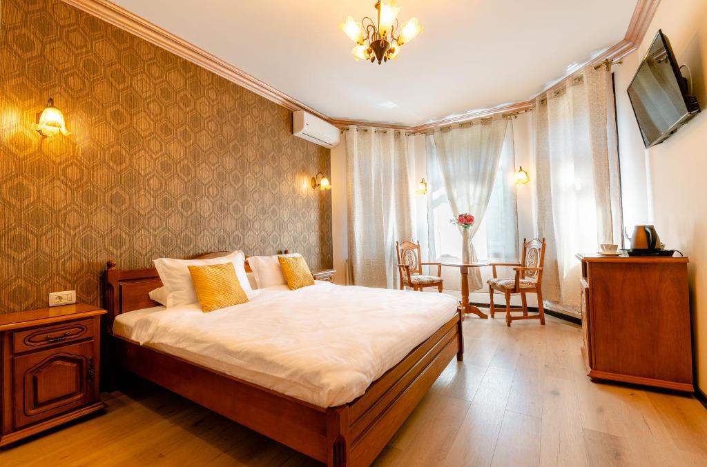 a bedroom with a bed and a table with chairs at Vila Genia in Câmpulung Moldovenesc