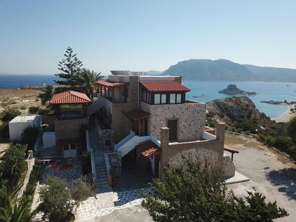 a large house on top of a hill next to the ocean at Panorama Studios in Kefalos
