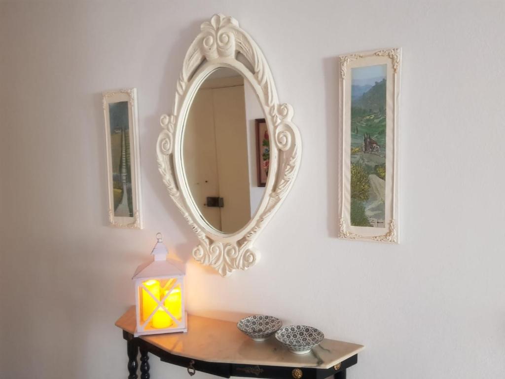 einen Spiegel an einer Wand mit einem Tisch und einer Lampe in der Unterkunft casa per l'osticcio vista sulla val d'orcia in Montalcino