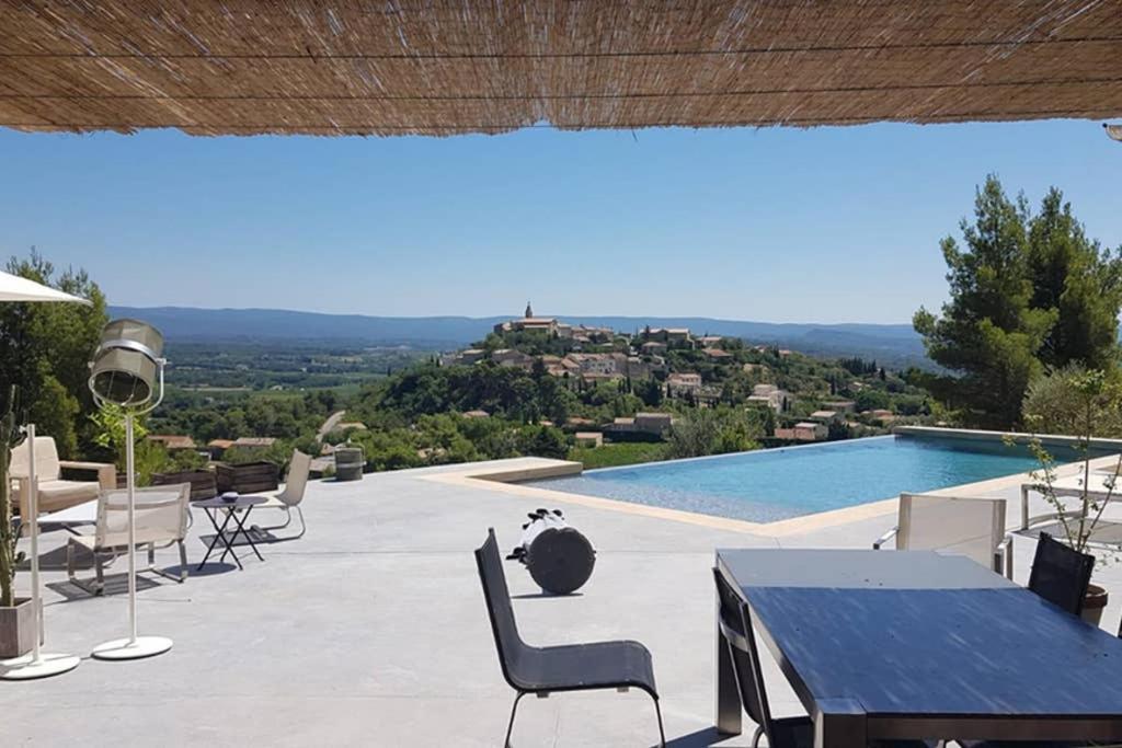 a patio with a table and chairs and a pool at Villa Font Garenne in Crillon-le-Brave