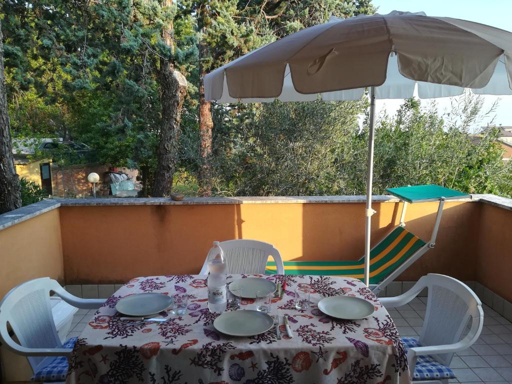 stół i krzesła pod parasolem na patio w obiekcie Appartamento Sirolo w mieście Sirolo