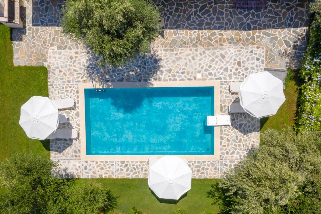 uma vista sobre uma piscina com guarda-sóis brancos em Michaelo Villa - Affordable Luxury! em Kalamaki