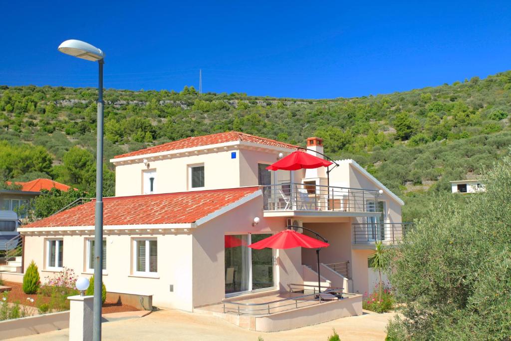 a house with two red umbrellas on the balcony at D&A Apartments in Vela Luka