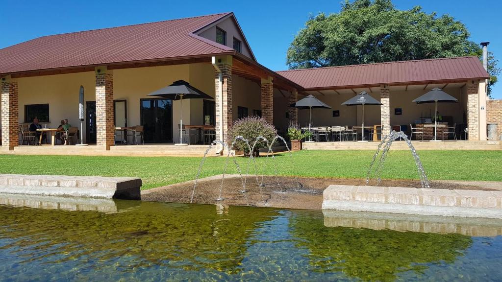 a fountain in the water in front of a building at Esther's Country Lodge in Hekpoort