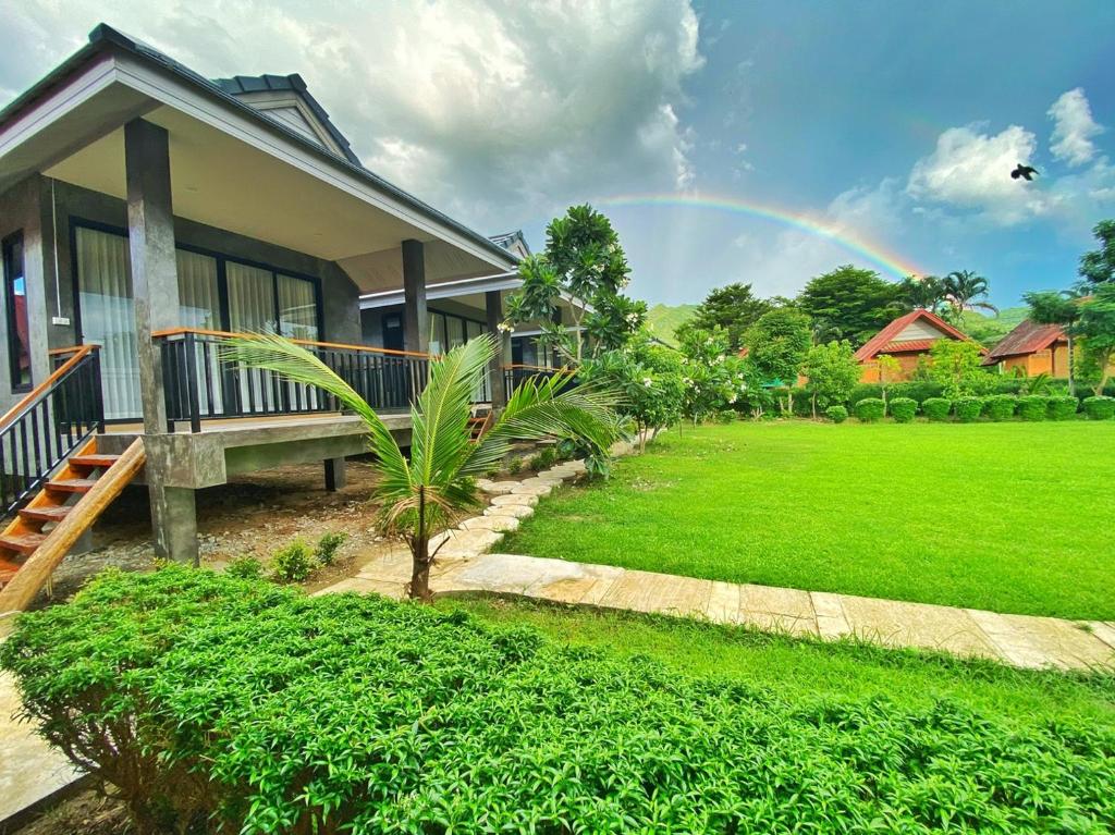 a rainbow over a house with a green yard at Pai Nam Now in Pai