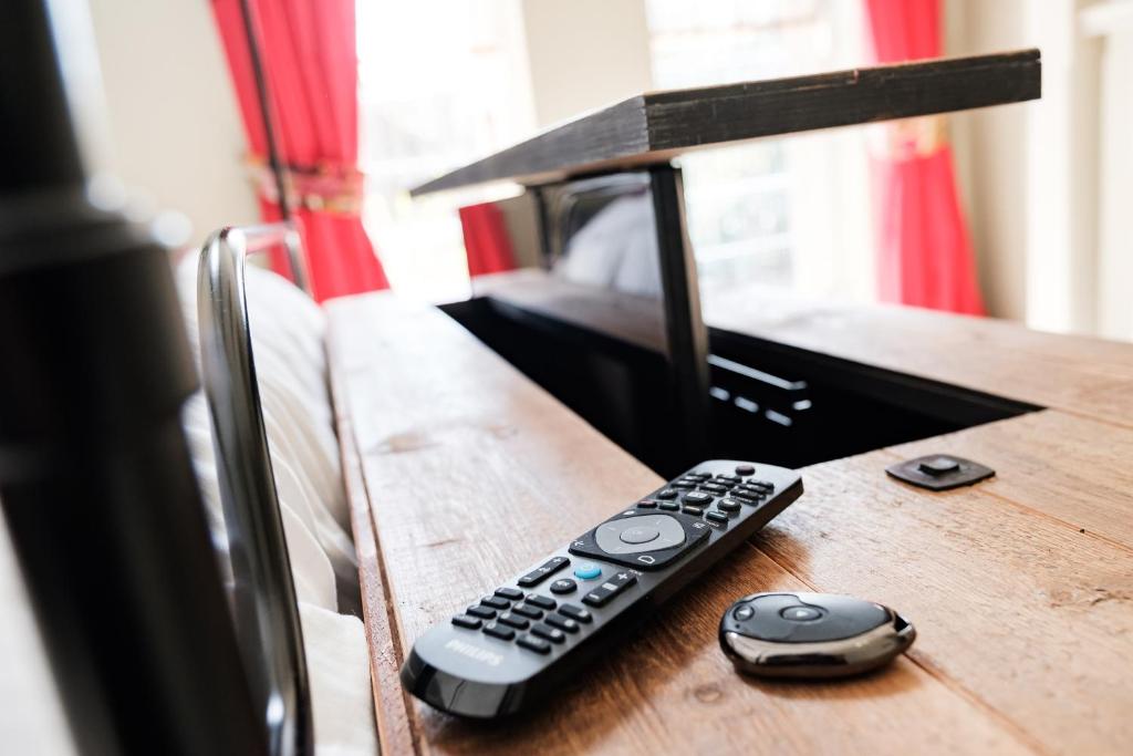 two remote controls sitting on top of a wooden table at Wykeham Arms in Winchester
