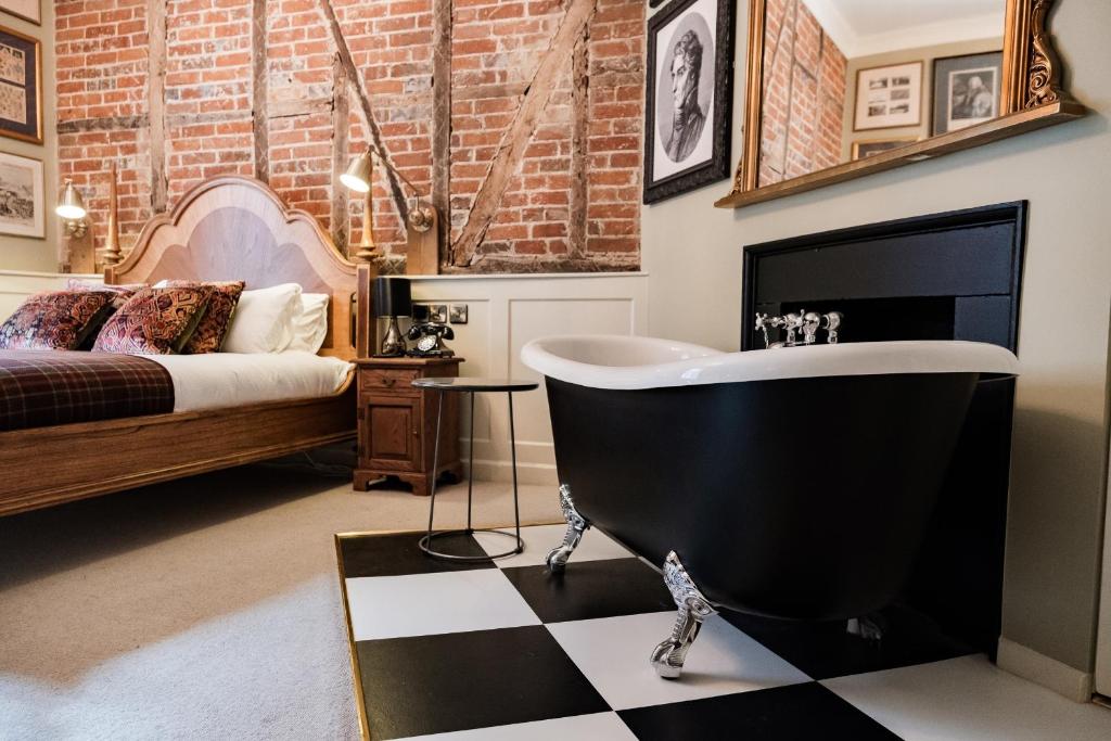 a bathroom with a black tub and a bed at Wykeham Arms in Winchester