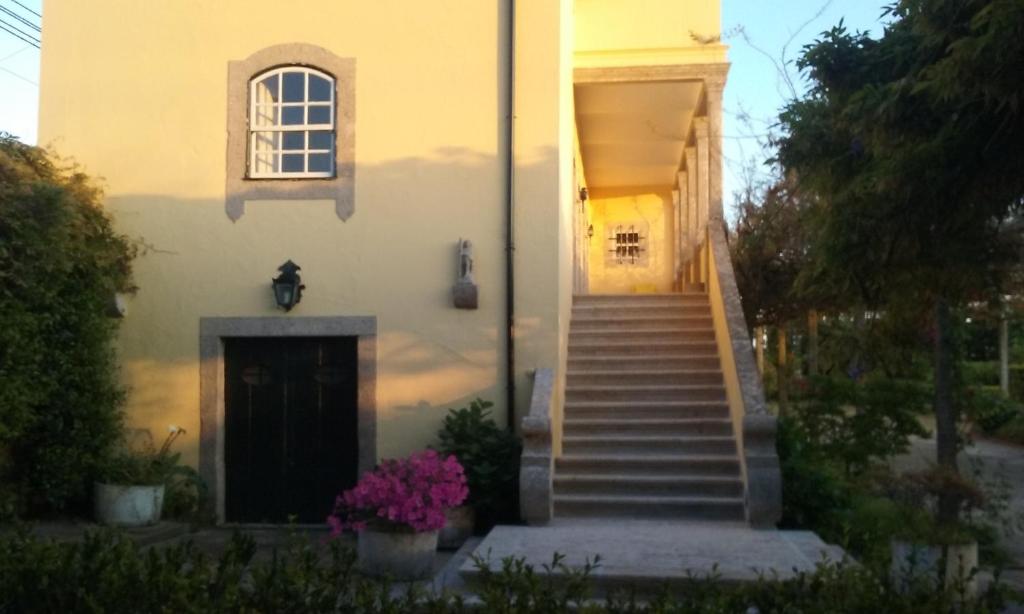 una casa blanca con escaleras y una puerta y flores en Casa de São João en Viana do Castelo