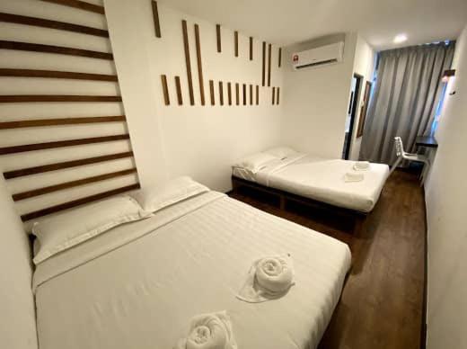 Kuching Hotel في كوتشينغ: غرفة فندقية بسريرين ومرآة