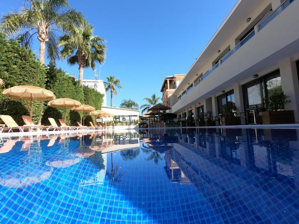 a swimming pool with chairs and umbrellas next to a building at Paradise Bar Apartments in Planos