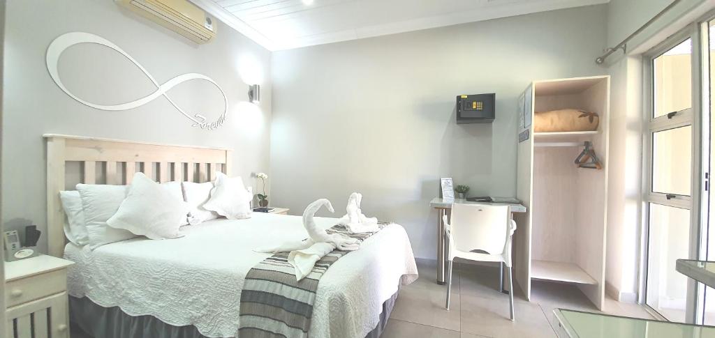 a bedroom with a bed with white sheets and a desk at Dive Inn Guesthouse in Pongola