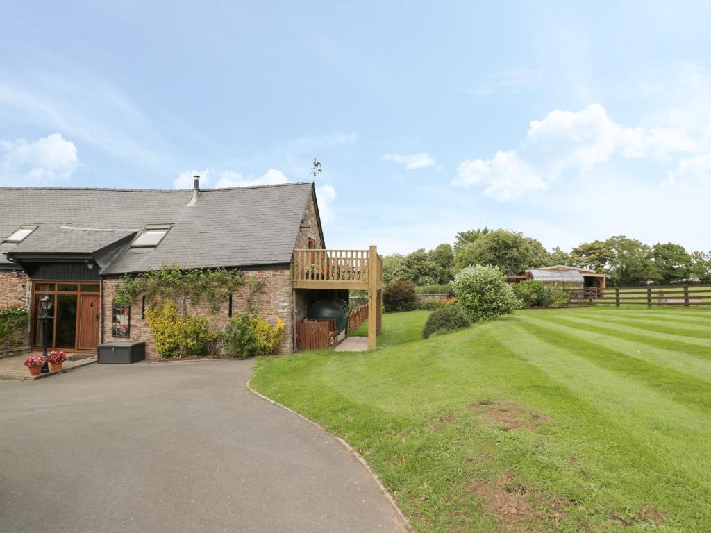 uma casa de pedra com um alpendre e um relvado em Pentre Barn em Abergavenny