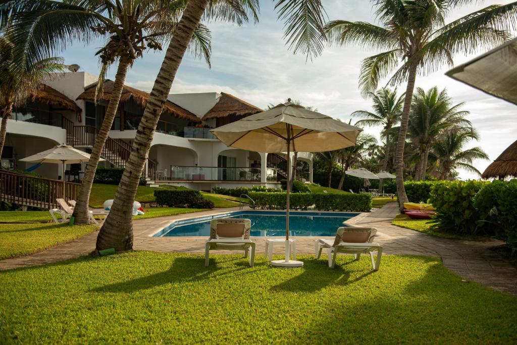 a resort with a pool and two chairs and an umbrella at Las Villas Akumal in Akumal