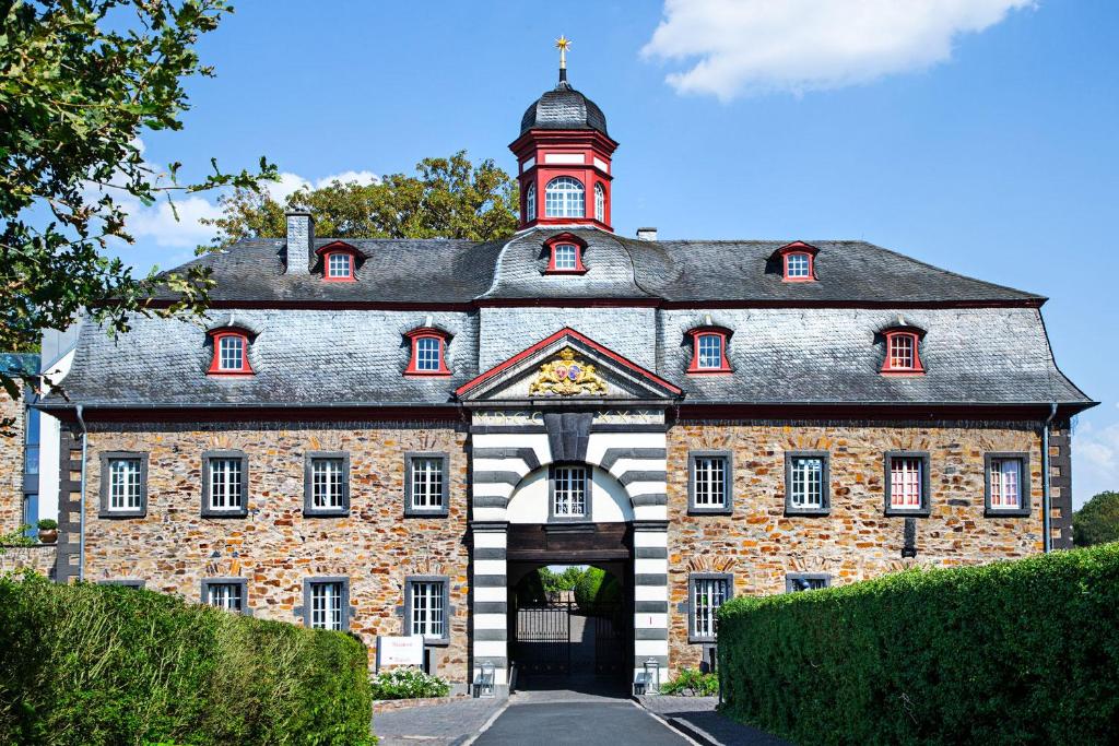 un grand bâtiment en briques avec une tour d'horloge en haut dans l'établissement Schloss Hotel Burgbrohl, à Burgbrohl