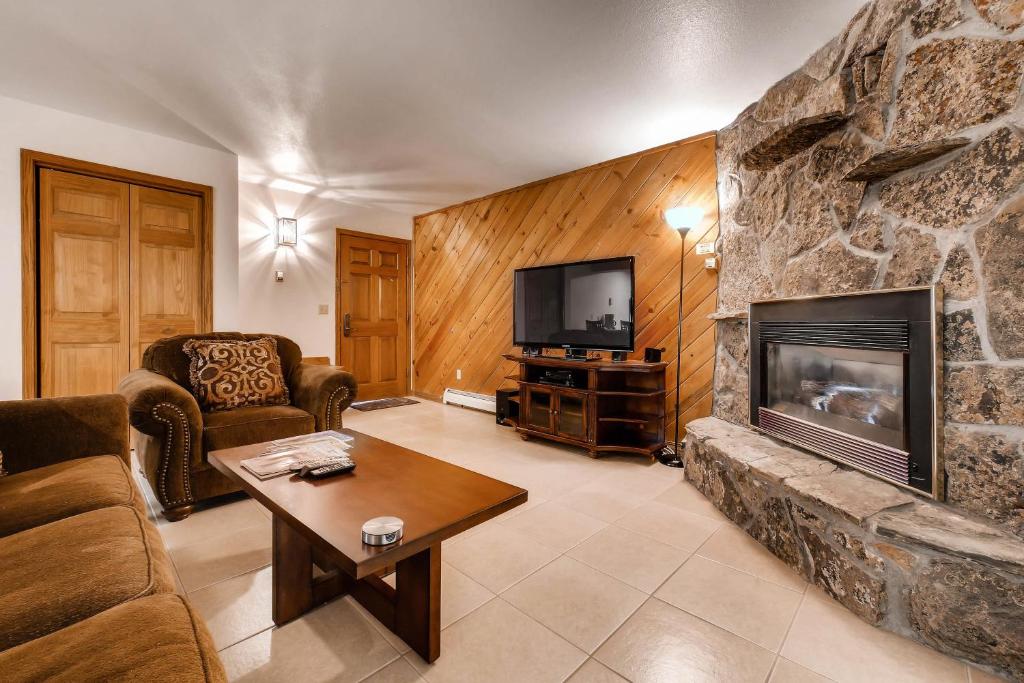 a living room with a stone fireplace and a tv at Phoenix I in Steamboat Springs