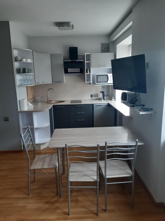 uma cozinha com mesa e cadeiras e uma televisão em Atmodas studio em Liepāja