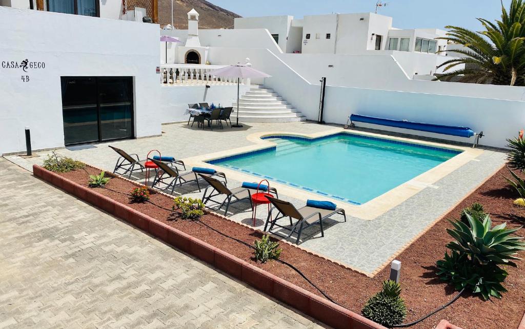 a swimming pool with chairs and a table next to a building at CASA GECO in Playa Blanca