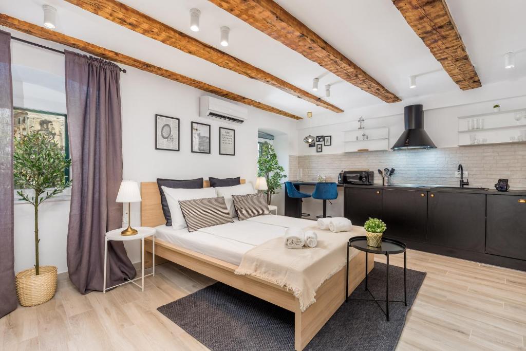 a bedroom with a large bed and a kitchen at Grota apartments in the center in Rijeka