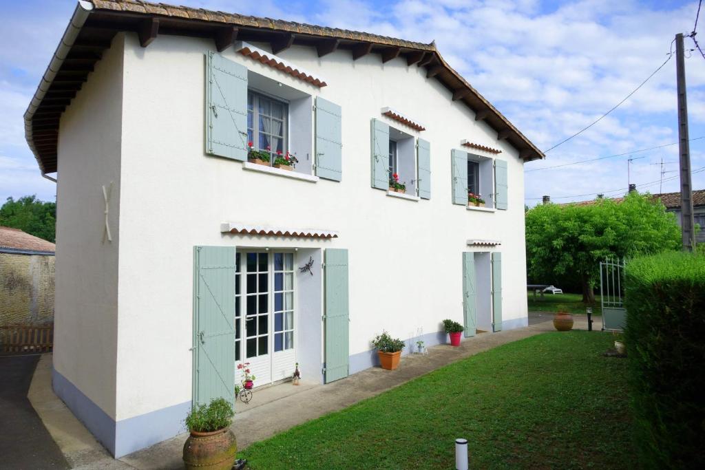 Casa blanca con puertas y ventanas verdes en AU COEUR DU MARAIS, en Saint-Hilaire-la-Palud