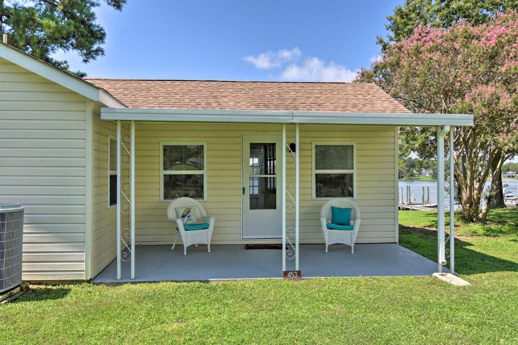 a screened in porch on a yellow house with two chairs at Romantic Waterfront Abode with Patio and Dock! in Deltaville