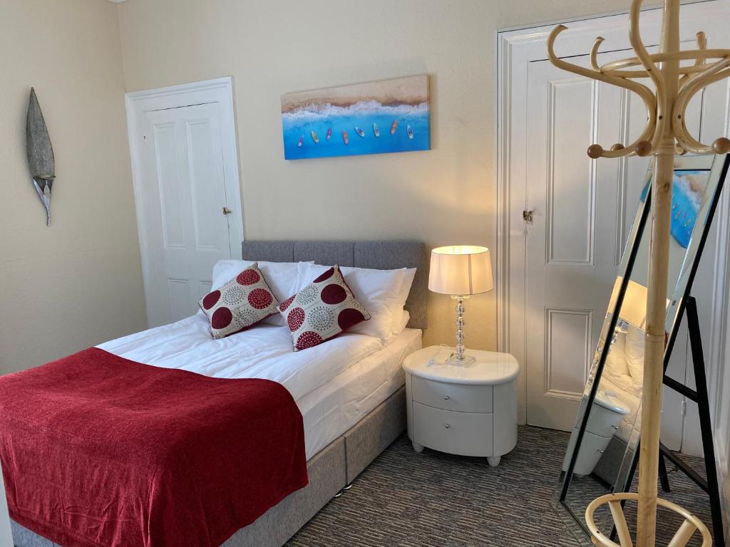 um quarto com uma cama com um cobertor vermelho em Serviced Property Apartment em Plymouth
