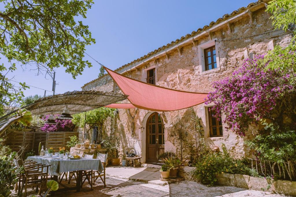 una zona de comedor al aire libre de una casa de piedra con una tienda roja en Can Recó, casa bohemia en el campo en Sant Llorenç des Cardassar