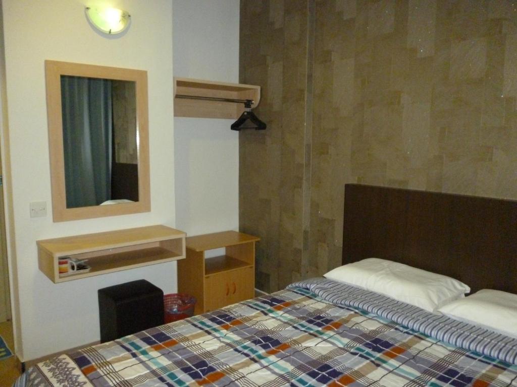 a small bedroom with a bed and a mirror at G Six Hotel in Sitiawan