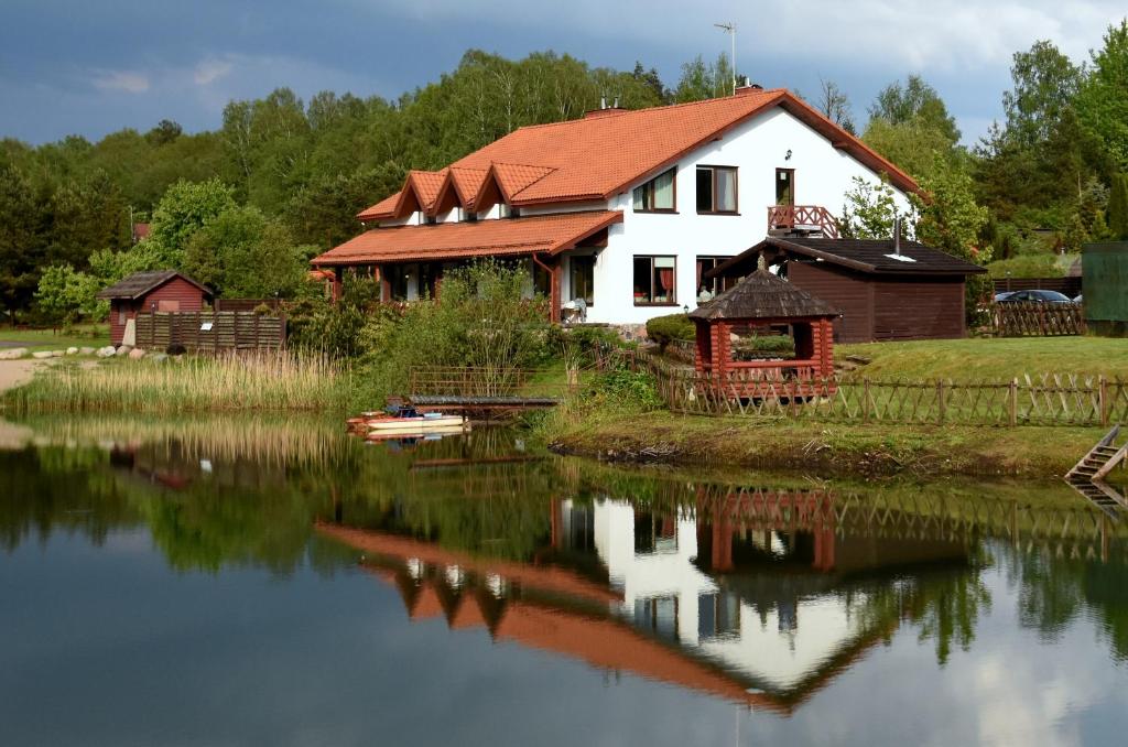 una casa sulla riva di un lago con una barca di Gervaičių Sodyba a Dovilai