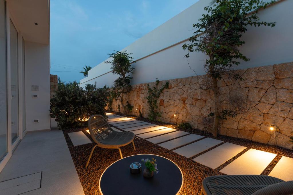 a patio with a table and chairs and a stone wall at Santa Caterina - Dimora sul mare in Polignano a Mare
