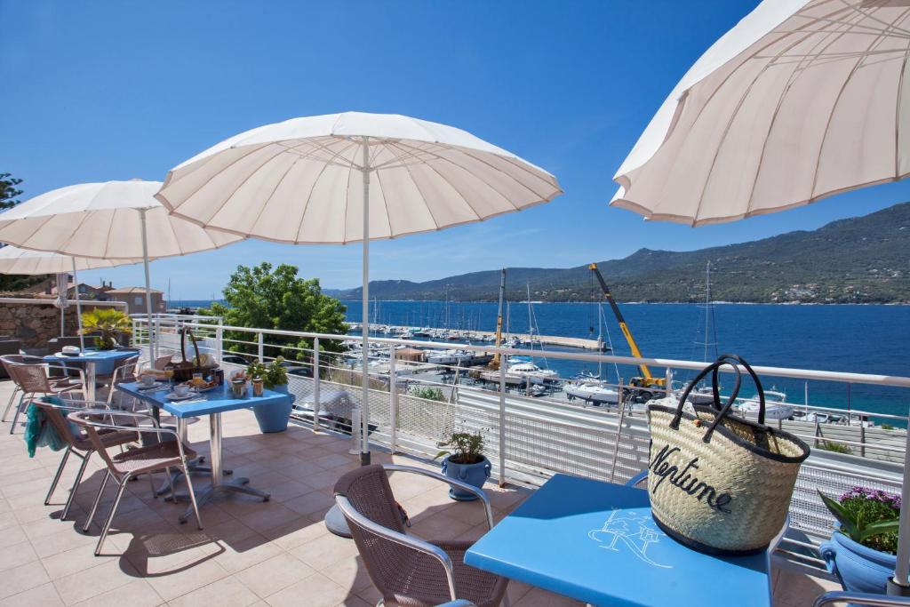 un patio con tavoli e ombrelloni e vista sull'acqua di Le Neptune & Spa a Propriano