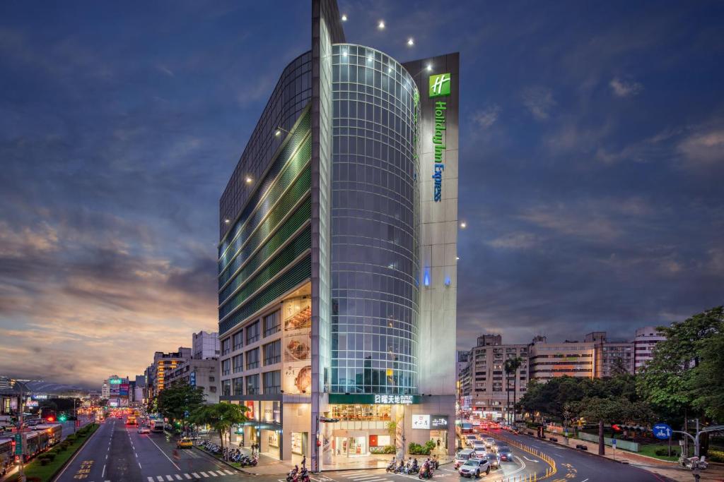 a tall glass building on a city street at night at Holiday Inn Express Taichung Park, an IHG Hotel in Taichung