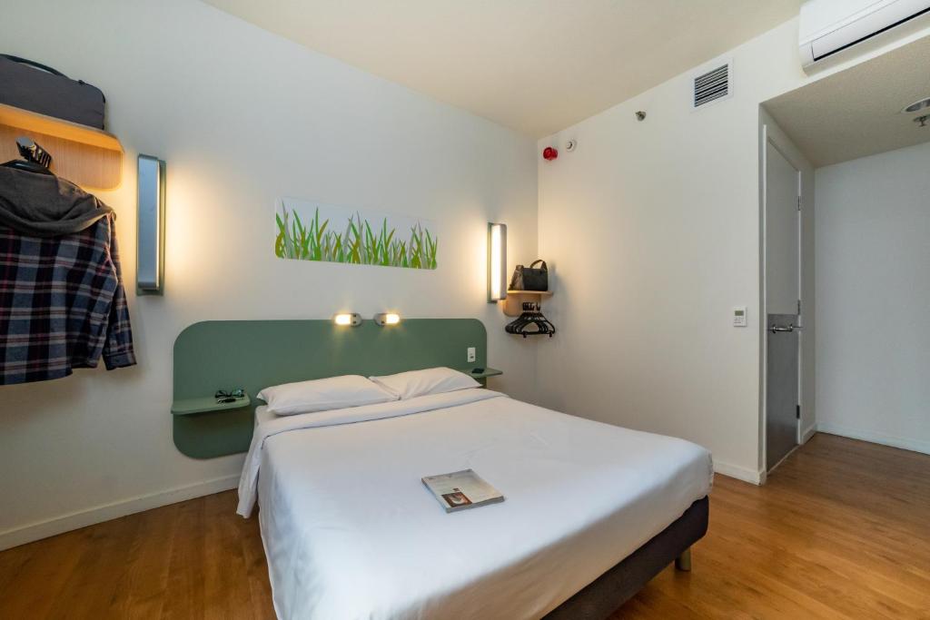 een slaapkamer met een wit bed met een groen hoofdeinde bij ibis budget SP Frei Caneca in Sao Paulo
